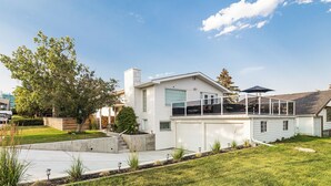 Une maison moderne à deux étages, dotée d’un grand garage, d’un patio couvert et d’une pelouse bien entretenue.