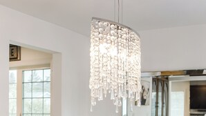 Un coin repas avec une table en bois foncé, un vase blanc orné de fleurs et un lustre.
