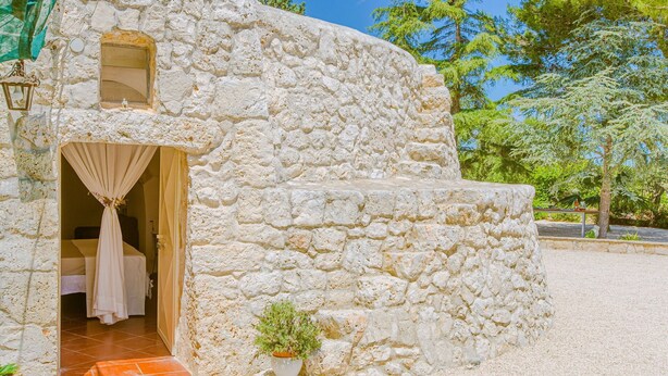 Un bâtiment en pierre avec une petite entrée, une fenêtre et un pot de fleurs.