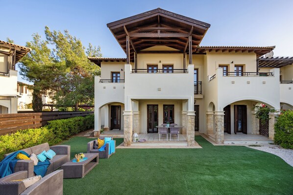 A two-story house with a patio, outdoor furniture, and a well-maintained lawn. - Zc02 Adjacent to Aphrodite Hills- Communal Pool, Garden (Kouklia)