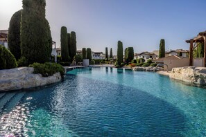 A swimming pool with clear water, surrounded by neatly trimmed hedges and tall trees. - Zc02 Adjacent to Aphrodite Hills- Communal Pool, Garden (Kouklia)