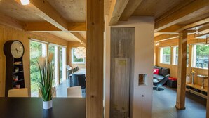 A modern wooden interior with a dining area, a living room with a sofa and a fireplace, and a large window offering a view of the outdoors. - Nice apartment in villa for 8 guests with WIFI, pool, TV and terrace (Annaberg Im Lammertal)