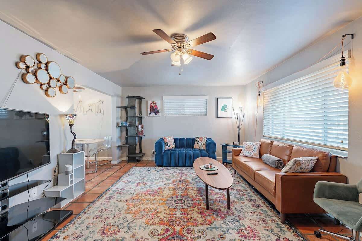 A living room with a TV, sofa, coffee table, and a ceiling fan.