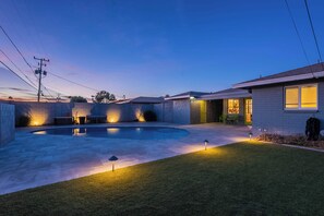A backyard with a swimming pool, a patio area, and a house with a visible door and windows. - Charming Oasis in Heart of Tempe, With a Pool! (Tempe)