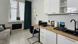 A modern kitchen with a wooden countertop, a sink, and a window with blinds. - Studio Bajka - 365PAM (Mielno)