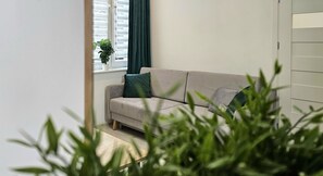A modern living room with a sofa and a potted plant by the window. - Studio Bajka - 365PAM (Mielno)