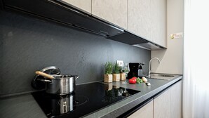 Een moderne keuken met een zwart aanrecht, roestvrijstalen apparatuur en een bordje met de tekst 'Niet roken, alstublieft'.