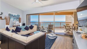 A modern living room with a sofa, a dining area, and a balcony with a view of the ocean. - Prime Ocean Front at Sonoran Sun W602 (Puerto Peñasco)