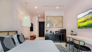 Une chambre d’hôtel moderne dotée d’un grand lit, d’un coin repas, d’une cuisine et d’une télévision.