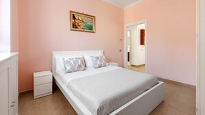 Um quarto com uma cama, mesas de cabeceira, cômoda e um quadro na parede.