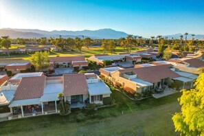 A residential area with houses featuring red-tiled roofs, some with attached garages, and a golf course in the background. - Fairway Retreat | 2BR Resorter (Palm Desert)