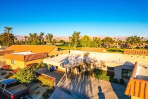 A residential area with houses, a parking lot, and a clear view of distant mountains. - Fairway Retreat | 2BR Resorter (Palm Desert)