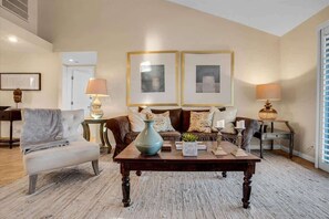 A living room with a sofa, armchair, coffee table, and two lamps. - Fairway Retreat | 2BR Resorter (Palm Desert)