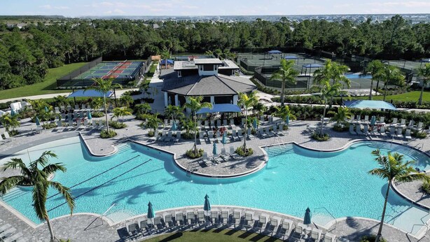 Et resort med en stor swimmingpool i midten, liggestole og udsigt over det omkringliggende landskab.