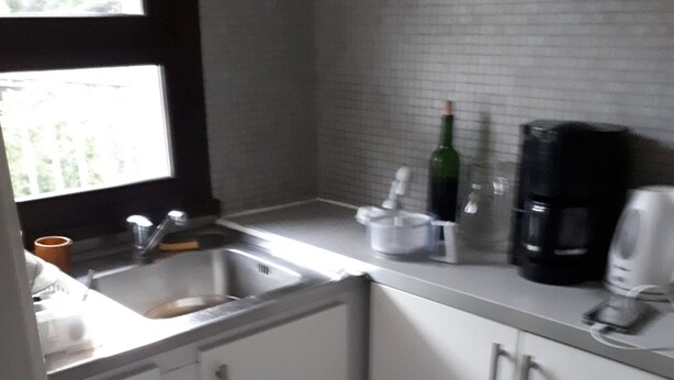 Cucina con pensili bianchi, lavello e macchina per il caffè.