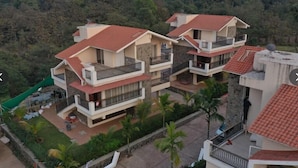 Un immeuble résidentiel à plusieurs étages, doté de balcons, entouré de verdure et situé dans un paysage vallonné.