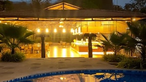 Vue sur une piscine d’hôtel, avec un bar, des espaces de détente en plein air et la piscine elle-même.