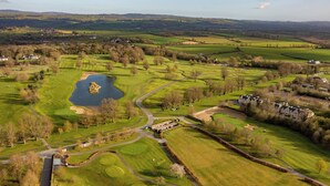 Un parcours de golf avec un étang, un club-house et des terrains environnants.
