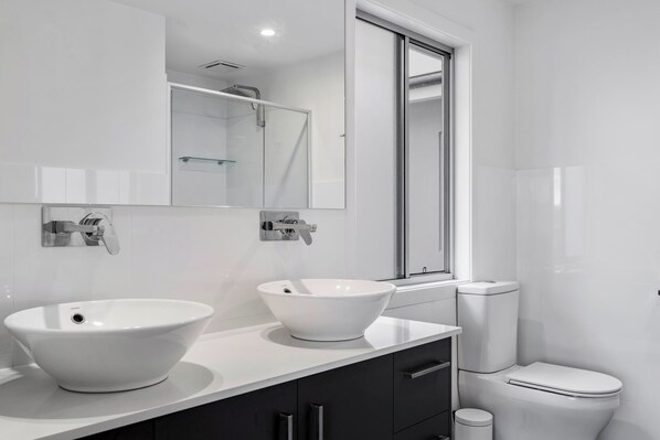 Une salle de bain moderne avec un grand lavabo blanc, un miroir et des toilettes.