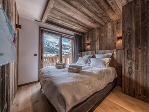 Relax in this serene bedroom with a large bed, surrounded by a simple design and a stunning mountain view.