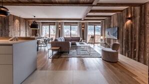 Ein großzügiger Wohnbereich mit Holzboden, einer Couch, einem Couchtisch und einem an der Wand befestigten Fernseher.