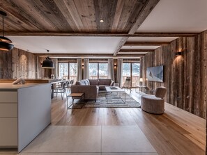 Relax in a spacious living space with a central seating area, dining area, and kitchen, offering views of the surrounding landscape.