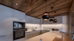 Eine moderne Küche mit Holzbalkendecke, Edelstahlgeräten und Pendelleuchten.