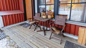 A wooden deck with a table and chairs, a bench, and a door. - Petsukka by Interhome (Kittilä)