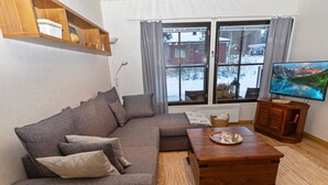 A living room with a sectional sofa, a wooden coffee table, a television, and a window with curtains. - Petsukka by Interhome (Kittilä)