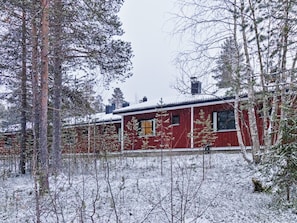 A red building with multiple windows, surrounded by snow-covered trees and a snowy landscape. - Petsukka by Interhome (Kittilä)