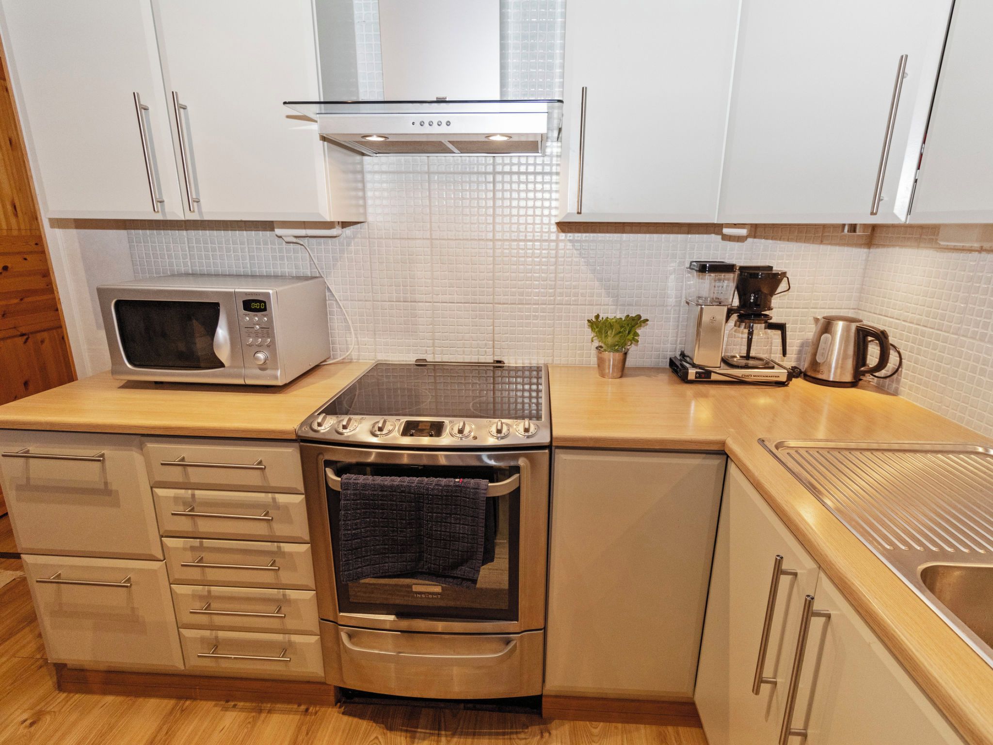 Cozinha compacta com micro-ondas, cafeteira e forno.