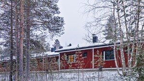 A red wooden cabin surrounded by snow-covered trees. - Petsukka by Interhome (Kittilä)