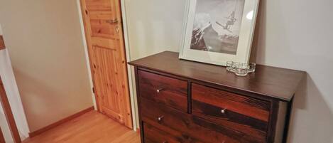 Un aparador de madera con cajones y un cuadro encolado encima.