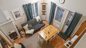 Un espacio habitable compacto con sofá, mesa de comedor, sillas, una pequeña cocina y una chimenea.