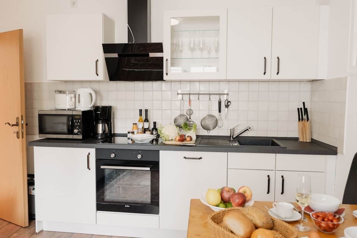 A modern kitchen with white cabinets, a black microwave, and a sink.