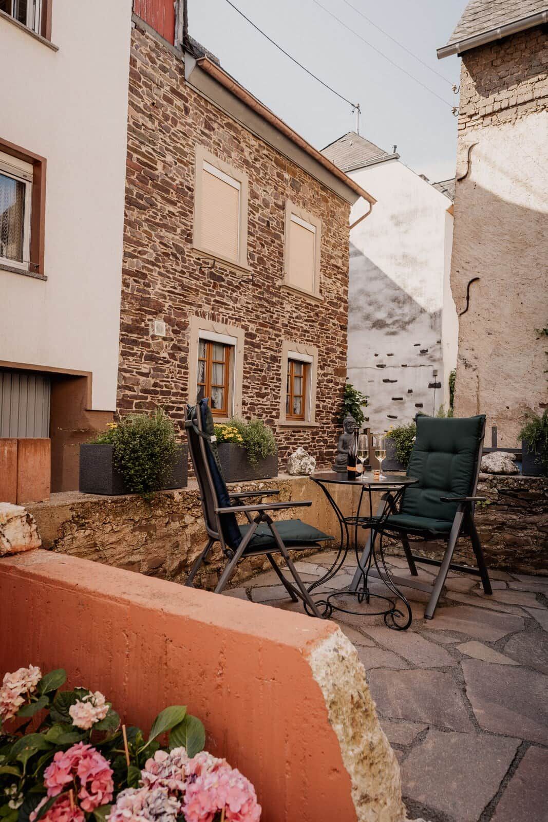 A stone building with a patio area featuring outdoor seating and a statue.