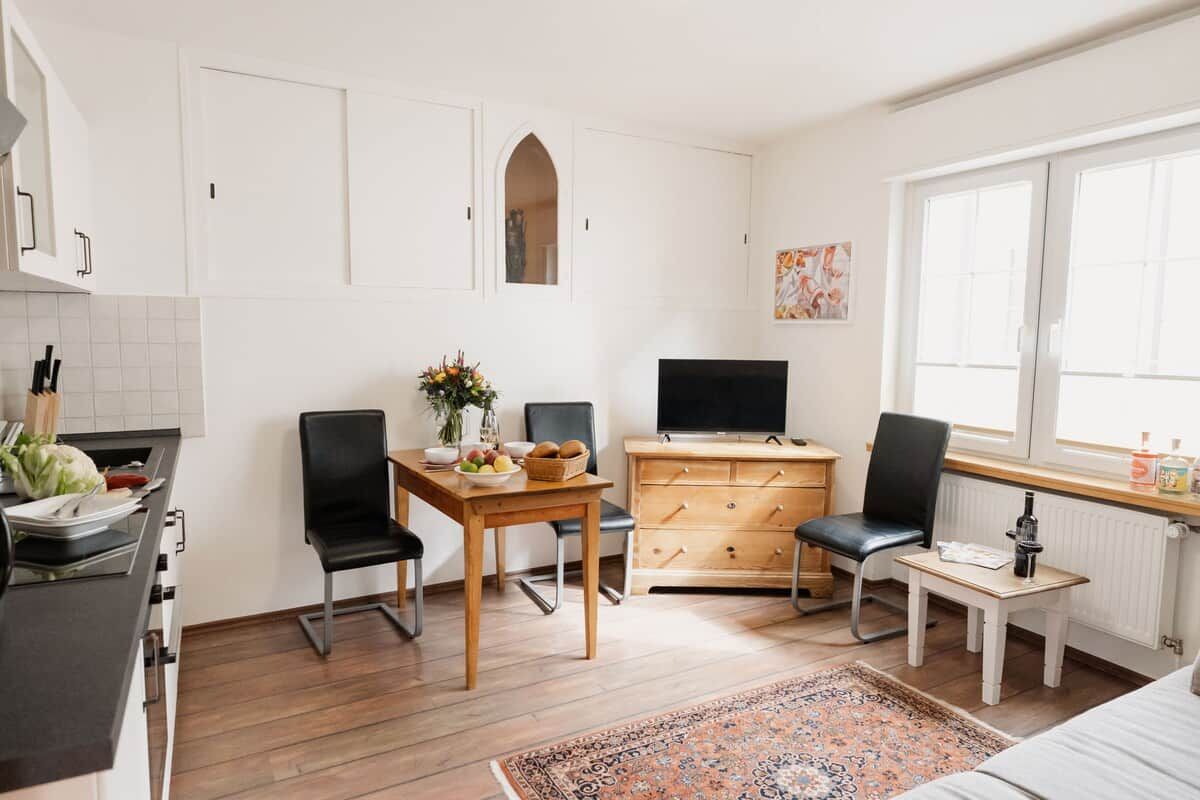 A compact living space with a kitchenette, a dining area, a television, and a window providing natural light.