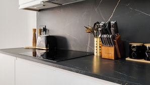 Eine moderne Küche mit einer schwarzen Marmorarbeitsplatte, einem Toaster, einem Messerblock und zwei Gläsern.