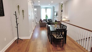 Ein modernes Wohnzimmer mit Essbereich, Holzboden und einer Treppe.