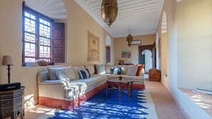 A cozy living room with a sectional sofa, a small round table, and a patterned rug. - Dar Salam, swimming pool, rooftop, staff, Medina (Marrakech)