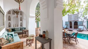 A traditional courtyard with a pool, seating area, and decorative elements. - Dar Salam, swimming pool, rooftop, staff, Medina (Marrakech)