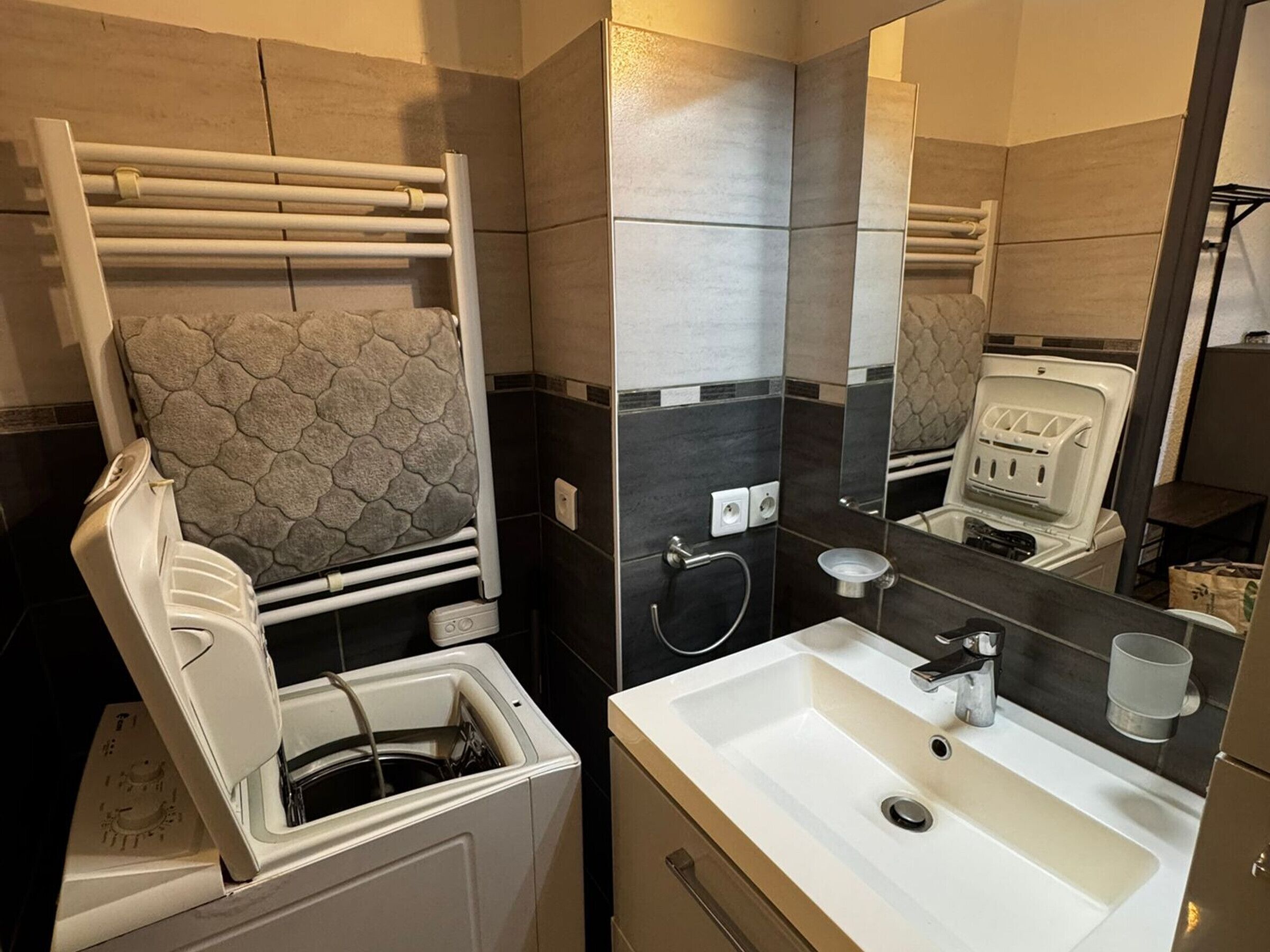 Un bagno moderno con lavandino bianco, porta asciugamani, specchio e cabina doccia.