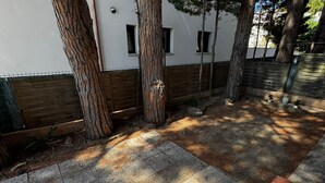 Sisäpiha, jossa on puita, valkoinen rakennus ja puinen aita.