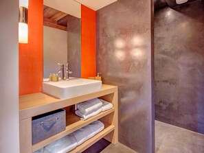 A modern bathroom with a white sink, wooden vanity, and a large mirror.