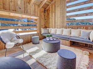 Interior acogedor de una cabaña con detalles de madera, un ventanal con vistas nevadas, un sofá cómodo y una mesa de centro redonda.