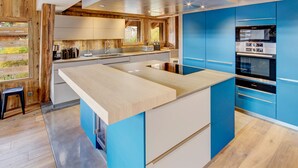 Une cuisine moderne avec un îlot central, des armoires bleues et un plafond en bois.