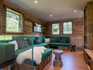 Ein gemütliches Zimmer mit einem grünen Sofa, einer Glastrennwand und Holzdielen.