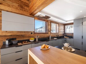 Enjoy cooking in this kitchen with a view, featuring a wooden accent wall and large windows overlooking the surrounding landscape.