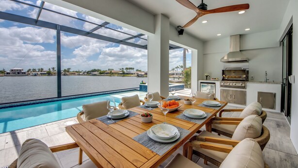 Un comedor moderno con vista a la piscina, mesa de madera y asientos cómodos.
