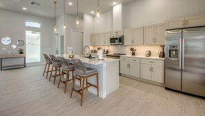Una cocina moderna con una isla central, electrodomésticos de acero inoxidable e iluminación colgante.